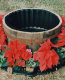 Wooden barrel-style pot surrounded by red flowers and protected by the flex-o-liner barrier.